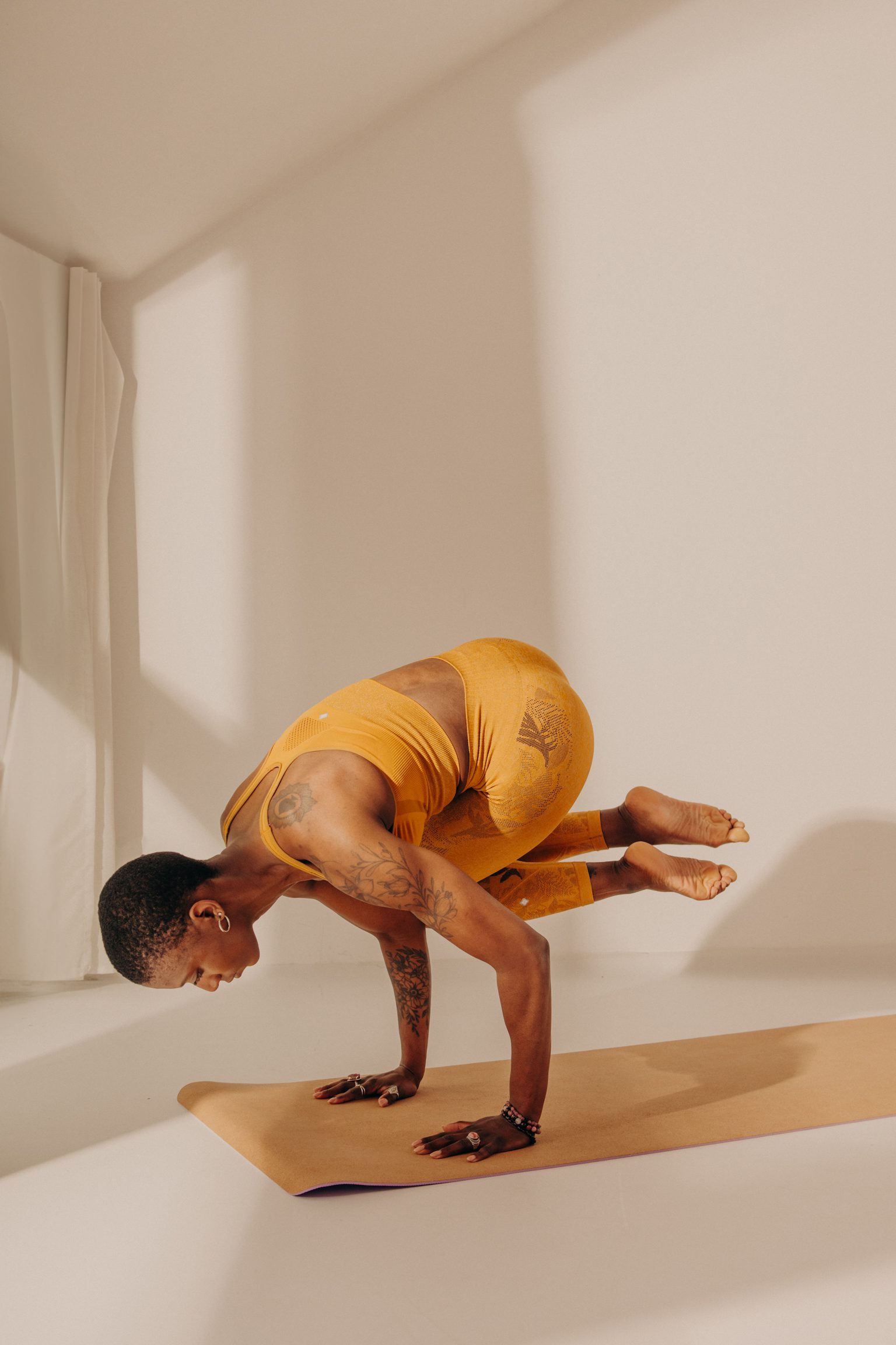 Femme noire en variation de Bakasana pendant un cours de Yoga Vinyasa à Orléans